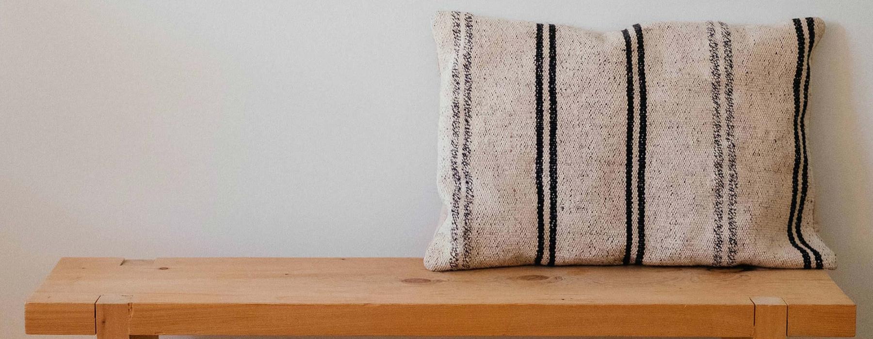 a wooden bench with a striped pillow on it